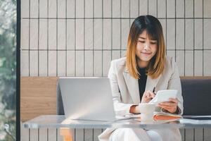 Smiling businesswoman using calculator and laptop at a sunny cafe, a perfect blend of technology and productivity. photo