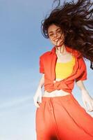 Smiling Woman Dancing in the Sunny Beach. Joyful Emotions and a Vibrant Summer Fashion Trend photo