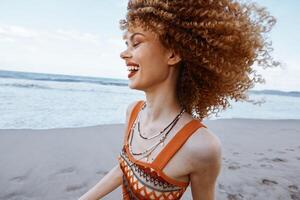Happy Hippie Woman Embracing Freedom on a Sunny Beach. Smiling Traveler with Curly Hair and Backpack photo
