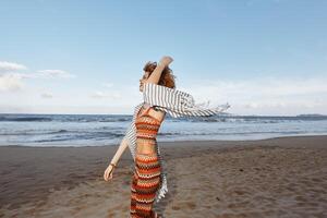 verano dicha. un sonriente mujer en un playa frazada, abrazando libertad y mar foto