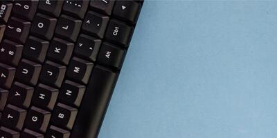 Close up of a black computer keyboard on a blue background with copy space photo