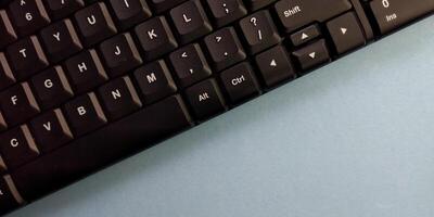 Close up of a black computer keyboard on a blue background with copy space photo