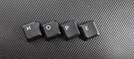 el palabra esperanza escrito con negro computadora llaves en un negro antecedentes. foto
