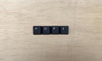 The word HOPE written with black computer keys on wooden background. photo