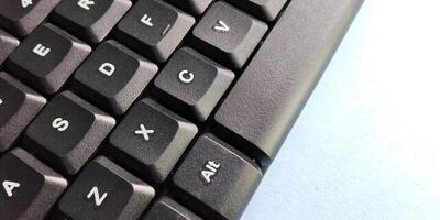 Close up of a black computer keyboard on a blue background with copy space photo
