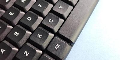 Close up of a black computer keyboard on a blue background with copy space photo