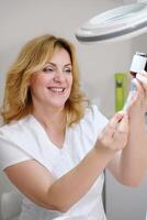 Smiling Cosmetologist Preparing a Syringe with Serum photo