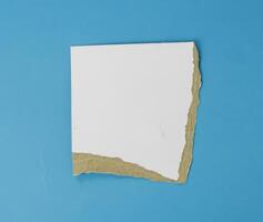 White paper teared on isolated blue background used for banner object design photo