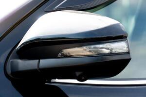 Close up of the mirror wing of a modern black car with turn light glass. With Blind Spot Monitoring System. photo