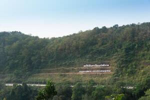 paisaje ver de montaña a Khao hundirse descanso detener uttaradit tailandia la carretera cortes mediante el montañas. y el tailandés texto medio Bienvenido. debajo azul cielo. foto