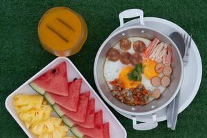 Pan Fried Eggs Topped with minced pork, hot flowers, Chinese sausage and crab sticks. Served in a galvanized plate and placed on a plate. Serve with watermelon and pineapple fruits. photo