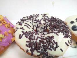 assorted donuts with chocolate frosted, pink glazed and sprinkles donuts. photo