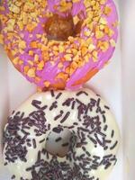 assorted donuts with chocolate frosted, pink glazed and sprinkles donuts. photo