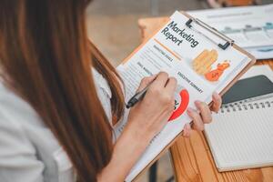 Business analytics concept, Close-up of a marketing professional critically reviewing a colorful marketing report, pen in hand, with a focus on business strategy. photo