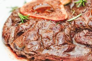 Cooked braised beef steak on the bone ossobuco with pepper, rosemary on the board photo