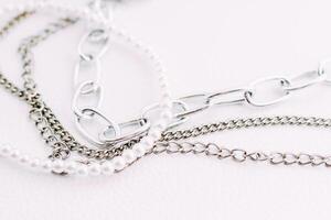 A necklace of white beads with chains of jewelry on a white aesthetic background. photo