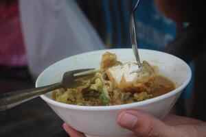 indonesio hombre come pollo fideos sopa felizmente a un comida puesto foto