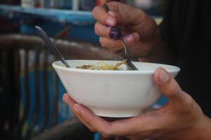 indonesio hombre come pollo fideos sopa felizmente a un comida puesto foto