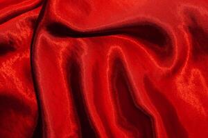 Red shiny texture of silk satin satin with folds. photo