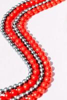 A necklace of red and gray beads on a white aesthetic background. photo