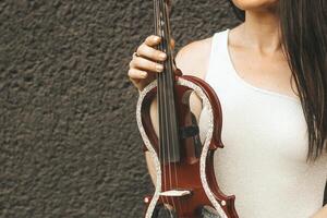 un fragmento de un eléctrico violín, un violín en el manos de un del músico muchacha. foto