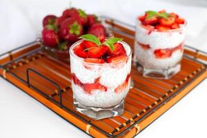Healthy breakfast of strawberry, yogurt and chia seeds on on a wicker tray. Homemade natural dessert. photo