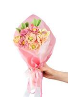 Women's hand holds a bouquet of flowers made from white Belgian chocolate isolated on white background. Close-up. photo