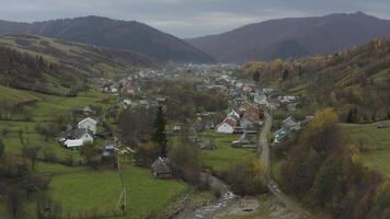 een dar vliegt over- een dorp in de bergen in de herfst video