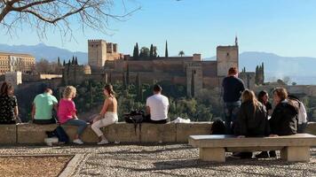 granada, España - 21 febrero 2024- personas y turistas caminar mediante el san nicolas punto de vista y tomar fotografías, observar el Alhambra y sierra Nevada en el antecedentes. video