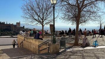 granada, Spagna - 21 febbraio 2024- persone e turisti camminare attraverso il san nicolas punto di vista e prendere fotografie, osservare il Alhambra e sierra Nevada nel il sfondo. video