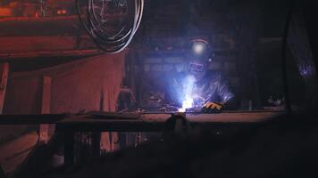 une soudeur dans une protecteur masque et cuir veste est soudage dans le sien atmosphérique atelier. faible clé. réel temps video