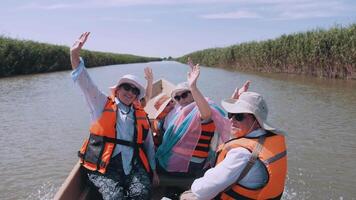 ein Gruppe von glücklich Touristen ist Segeln im ein Boot auf das Fluss. Alten Tourismus. Touristen im Leben Jacken. video