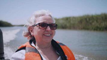 een vrouw geniet op reis terwijl het zeilen Aan een motor boot Aan de rivier. ouderen toerisme. gelukkig toerist. een veel van emoties. een emotioneel kader. video