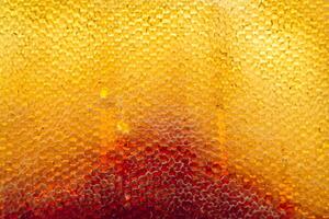 Drop of bee honey drip from hexagonal honeycombs filled with golden nectar photo