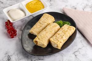 Homemade stuffed pancakes with honey and cream sour photo