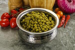 Sweet canned young green peas photo