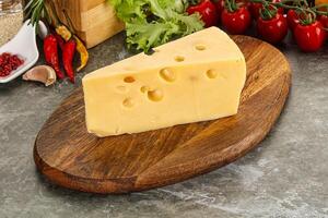 Swiss Maasdam cheese triangle over board photo