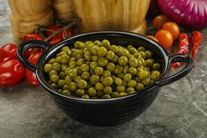 Sweet canned young green peas photo