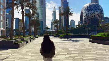 feliz menina com grandes cabelo rotaciona dentro a cidade com uma Visão do arranha-céus edifícios. Alto qualidade fullhd cenas video