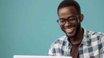 ai generado un alegre milenario chico en lentes usos un ordenador portátil computadora para en línea trabajo o comunicación como él soportes en frente de un azul estudio fondo foto