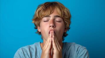 ai generado joven hombre con cerrado ojos meditando en contra azul antecedentes foto