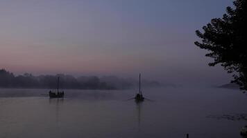 två gammal äkta trä- båtar på en sjö eller flod i de morgon- under en dimmig gryning. antal fot skott med naturlig morgon- belysning i 4k bakgrund med konstant fokus video
