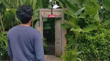 Jeune adulte entrer et aller en dehors de le porte vert jardin. le métrage est adapté à utilisation pour solo en voyageant, Voyage destination et la nature Contexte contenu médias. video