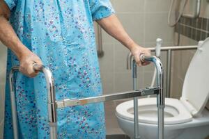 Asian elderly woman patient use walker and toilet bathroom handle security in nursing hospital, healthy strong medical. photo