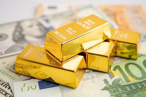 Gold bar on US dollar and Euro banknote, economy finance exchange trade investment. photo