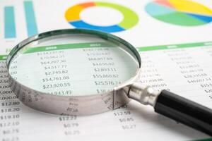 Magnifying glass on spreadsheet and graph paper. Financial development, Banking Account, Statistic, Investment Analytic research data economy, Business. photo