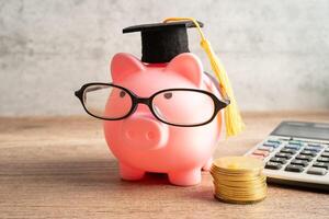 Pigging bank wearing eyeglass with with coins and calculator saving bank education. photo