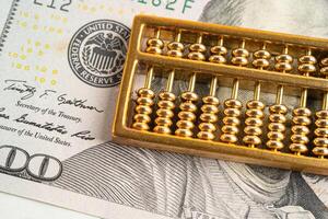 Gold abacus on US dollar banknote money, economy finance exchange trade investment. photo