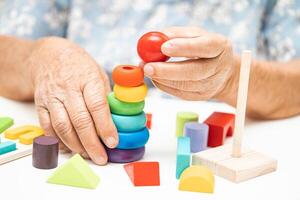 Alzheimer disease AD, Asian elderly woman patient suffering from dementia learn practical motor skills rehabilitation. photo