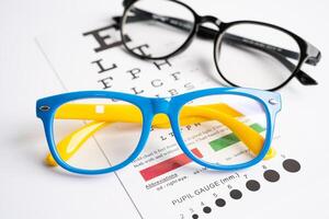Glasses on eye testing exam chart to check eyesight accuracy of reading. photo